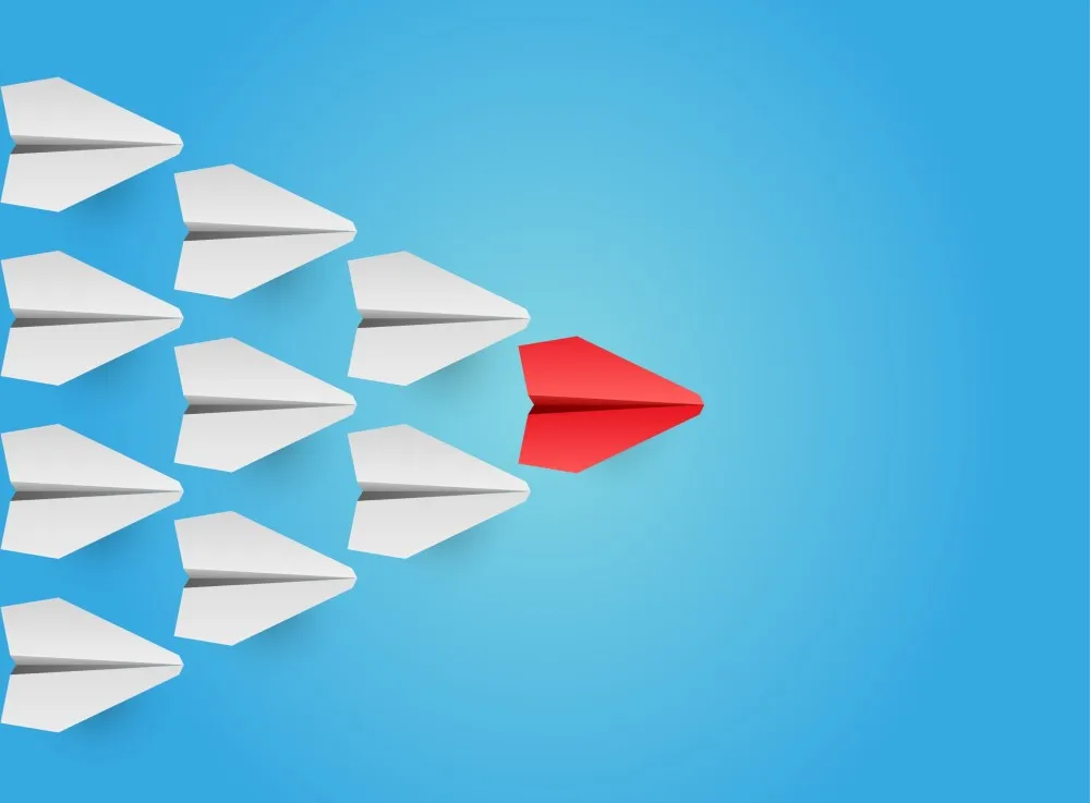 White paper planes in a wedge/pyramid formation flying left-to-right behind the leader, a red plane.